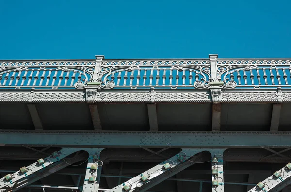 stock image Ornate fencing of old forged metallic bridge against blue sky shot from below