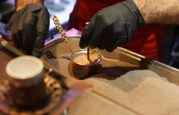 Making coffee on the sand close up, turkish coffee on a market, man in black gloves making coffee in turka