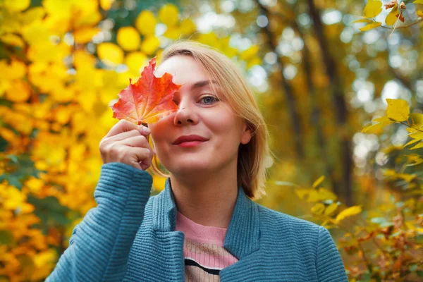 Usmívající Blondýnka Zakrývající Jedno Oko Červeným Javorovým Listem Podzimní Koncept — Stock fotografie