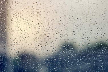 Yağmurlu bulutlu bir günde berrak cam üzerinde büyük yağmur damlaları