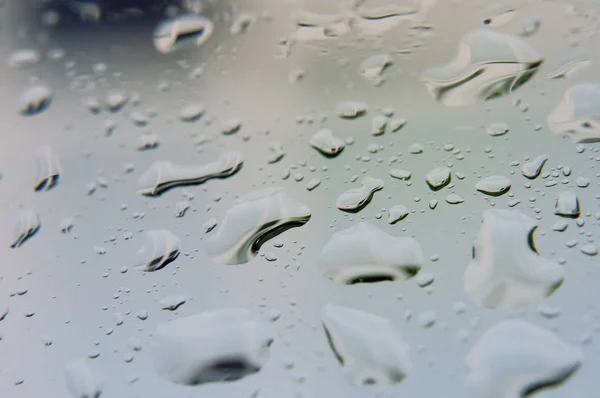 Grandi gocce di pioggia su vetro trasparente in una giornata nuvolosa piovosa — Foto Stock