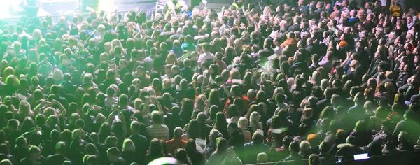 Uma grande multidão de pessoas em um concerto nos raios da música colorida — Fotografia de Stock