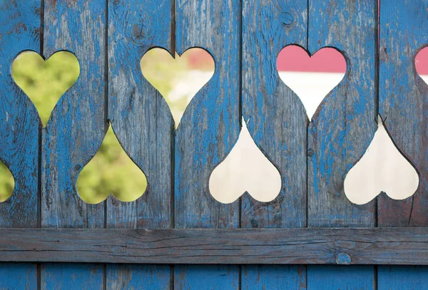 Wooden blue old fence with holes in the form of hearts