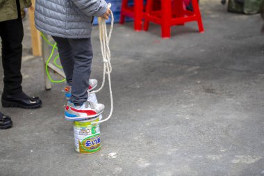 Açık parkta bir grup çocuk, ayaklıklar üzerinde çömelmek için süt tozu kutularını kullanarak, oynamak için eğlenceli bir çocuk oynamak için çok ilginç