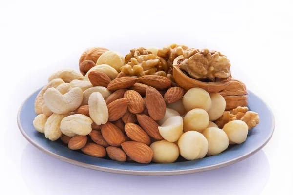 stock image Nutritious mixed nuts on the plate, walnuts, almonds, cashews, macadamia nuts