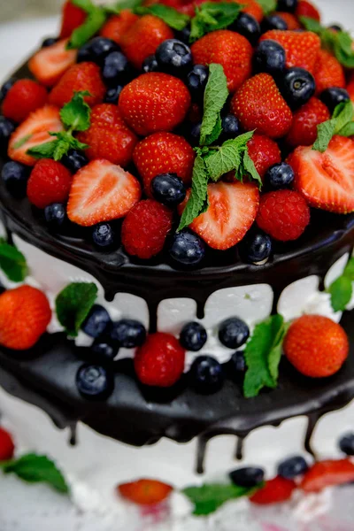 Wedding fruit cake with berries in chocolate glaze from tiers