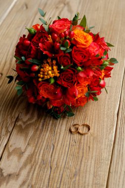 alyans ve ahşap bir arka plan üzerinde kırmızı çiçek bir buket