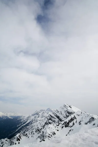 Montanhas na neve sobre um fundo de nuvens — Fotografia de Stock