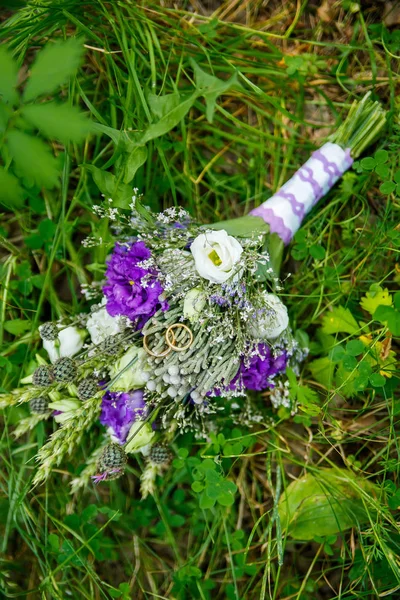 Guld vigselringar på bakgrunden av ett bröllop bukett — Stockfoto