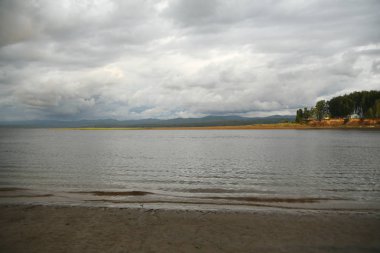 voluminous black thunderclouds over mountains and water at sunset