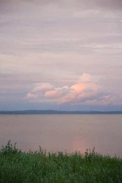 Volumetrische roze en blauwe wolken bij zonsondergang boven het water — Stockfoto