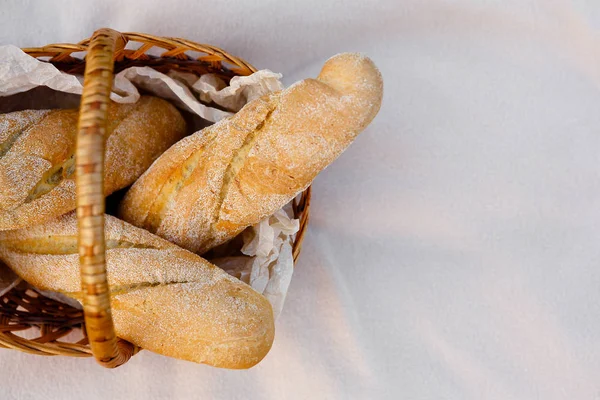 Tres baguettes frescos yacen en una canasta de mimbre — Foto de Stock