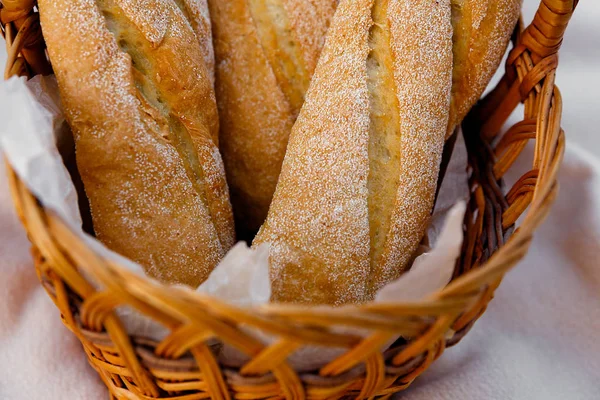 Tres baguettes frescos yacen en una canasta de mimbre — Foto de Stock