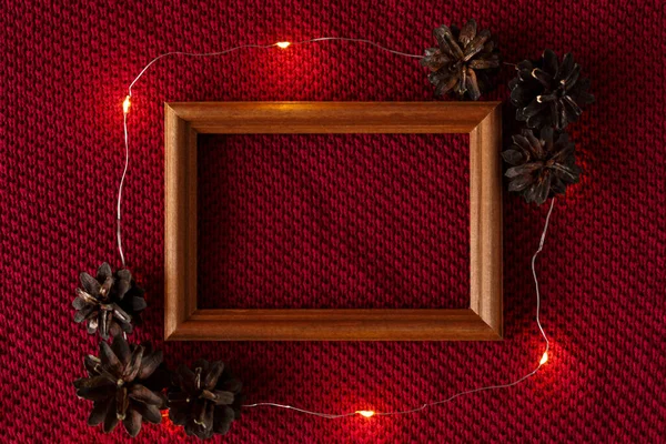 Christmas background. Cones, frame and garland lying on the knitted texture of a sweater. — Stock Photo, Image