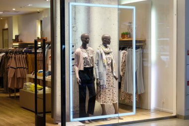 Bir alışveriş merkezindeki virgül butiğinin vitrininde giysili mankenler.