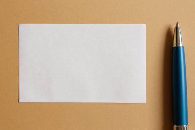 Kahverengi kağıt zemin üzerinde notlar için beyaz kağıt sayfa ve mavi metal kalem düz yatıyordu