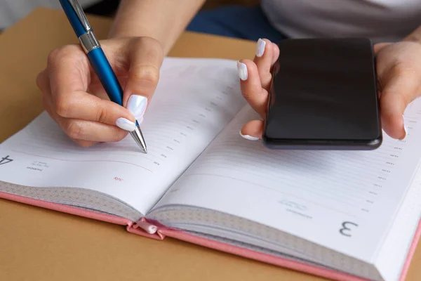 Mann Schreibt Mit Blauem Stift Tagebuch Und Hält Smartphone Der — Stockfoto