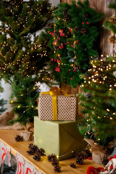 Christmas card. Gifts in boxes in craft packaging stand near the New Year tree on a brown wooden table