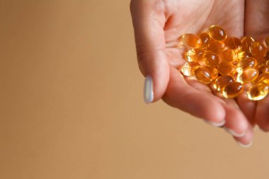 Kadın avuçlarında omega-3 vitamini kapsülü ya da tablet tutuyor. Sağlıklı beslenme ve yeme alışkanlığı..