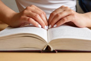 Bir kadın kitap okuyor. Elleri kitap tutuyor. Güzel manikür. Bir öğrenci bir ders kitabı okuyor. Eğitim ve bilgi eğitimi kavramı