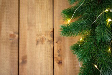 Noel arkaplanı. Kaba kahverengi tahtalarda çelenk olan yeşil ladin dalları.