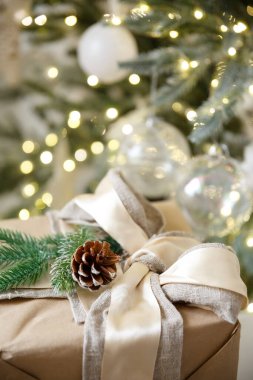 Tebrik kartı. Yanan bir Noel çelengi ve yılbaşı ağacının arka planında bir kutuda hediye.