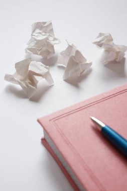 Pembe günlük ve beyaz arka planda mavi metal kalem, buruşmuş kağıt parçaları. Mektuptaki hatalar