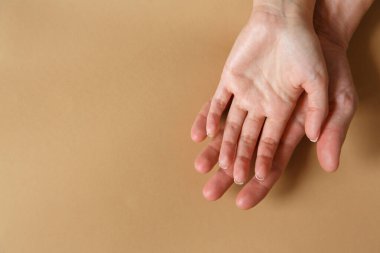 Erkek ve kadın elleri kahverengi arka planda yakın planda. Aşk, aile ve sadakat kavramı. Duygular ve tutumlar. Metin için boş boşluk