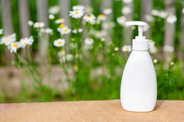 Sabun için beyaz kozmetik şişesi ya da papatya arkaplanlı ahşap rafta şampuan. Ürününüzün montajı için