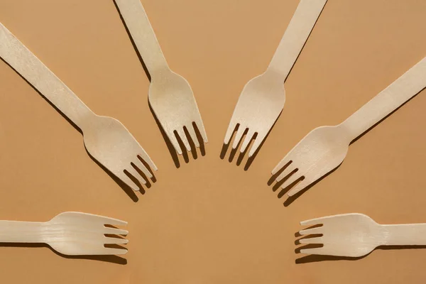wooden forks are laid out in a circle. Contrast lighting. Flat lay. Eco friendly wooden cutlery. Plastic Free Concept.