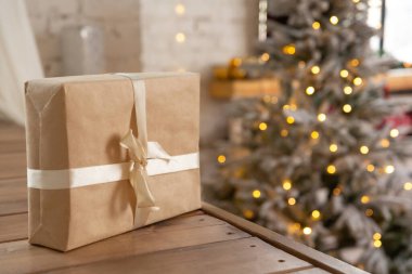 Noel çelenginin yanan arka planında, ahşap bir rafta duran hediye kutusu. Yeni yıl ya da Noel geçmişi. Tebrik kartı.