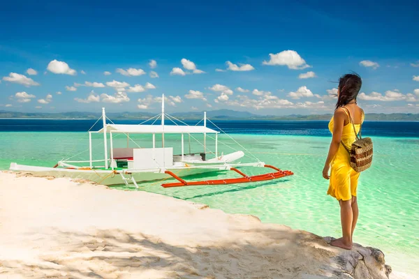 Młoda kobieta w żółtej sukience stojącej w cieniu na plaży an — Zdjęcie stockowe