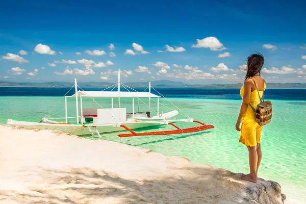 Jeune femme avec robe jaune debout à l'ombre ona plage un Photos De Stock Libres De Droits