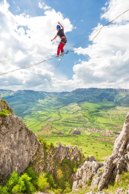 Genç slackliner adam iki kaya arasında bir gevşeklik üzerinde dengeleme. Arkasında güzel bir doğal manzara ile Highline