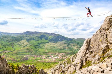 Genç slackliner adam iki kaya arasında bir gevşeklik üzerinde dengeleme. Arkasında güzel bir doğal manzara ile Highline