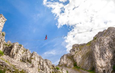 Genç slackliner adam iki kaya arasında bir gevşeklik üzerinde dengeleme. Arkasında güzel bir doğal manzara ile Highline