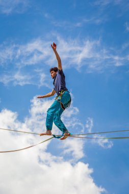 Genç slackliner adam iki kaya arasında bir gevşeklik üzerinde dengeleme. Arkasında güzel bir doğal manzara ile Highline
