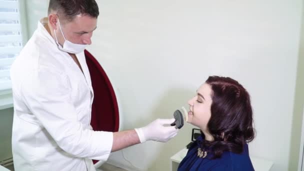 Стоматолог с образцами цвета зубов выбирает цвет зубов в стоматологической клинике — стоковое видео