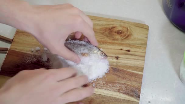 Man salter rå fisk på en skärbräda — Stockvideo