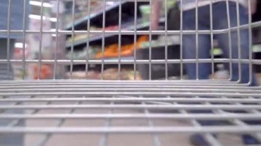 bakkal etrafında hareket eden boş alışveriş sepeti görünümü, insanlar arka planda bir dükkanda bakkal satın alıyor