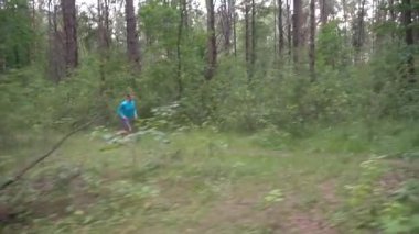 Yavaş çekim gri şortlu beyaz atlet ve ormanda koşan mavi uzun kollu sağlıklı yaşam tarzı kavramı.