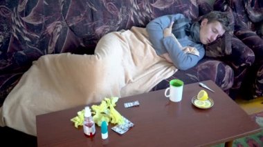 Hastalık sırasında ateşler içinde titreyen hasta bir adam ve evdeki kanepede yatan ateş belirtileri var.