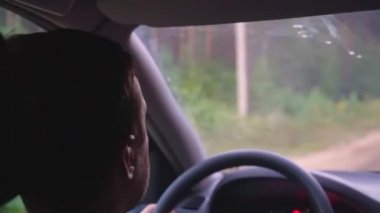 Kafkasyalı bir adam çakıl yolu boyunca ormanda araba kullanıyor.