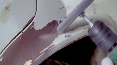 Vücut ustası eski boyayı ve paslı bedeni viski çemberli matkapla eziyor.