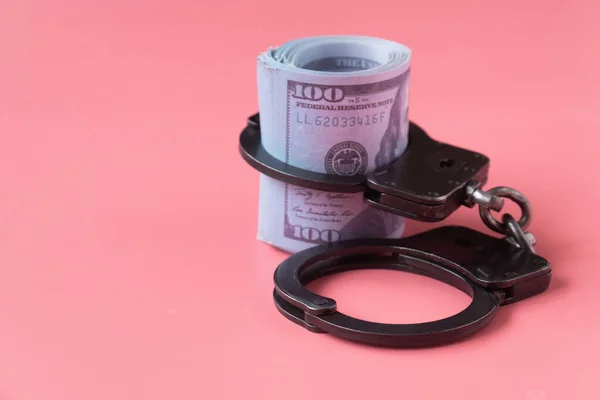 Pembe arka planda kelepçeli bir tomar dolar. Rüşvet ve yolsuzluk kavramı