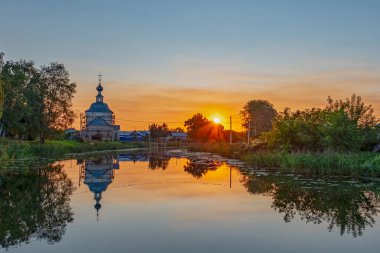 Rusya 'nın altın yüzüğü, Antik Suzdal şehri. Gün batımının arka planında, nehrin suyundaki yansımasıyla kilisenin güzel akşam manzarası.