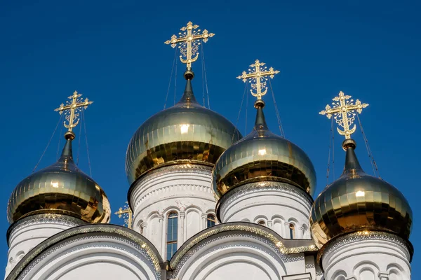 Church with golden domes and crosses on blue sky background.