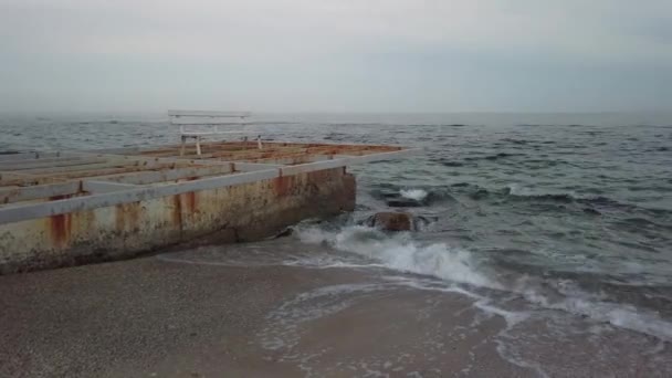 Old breakwater and empty bench in the evening - Pan — Stock Video