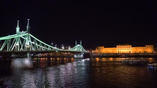 Boote unter der Freiheitsbrücke nachts beleuchtet — Stockvideo