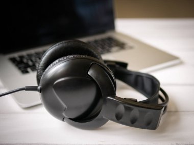 Dizüstü ve eski kulaklıklı beyaz ahşap çalışma masası